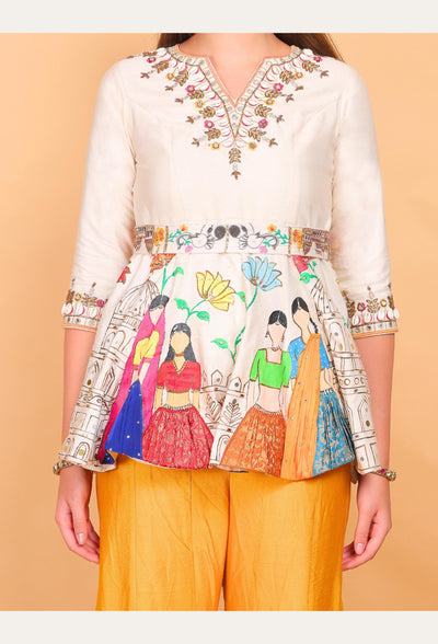 White embroidered top with colorful designs on a peach background