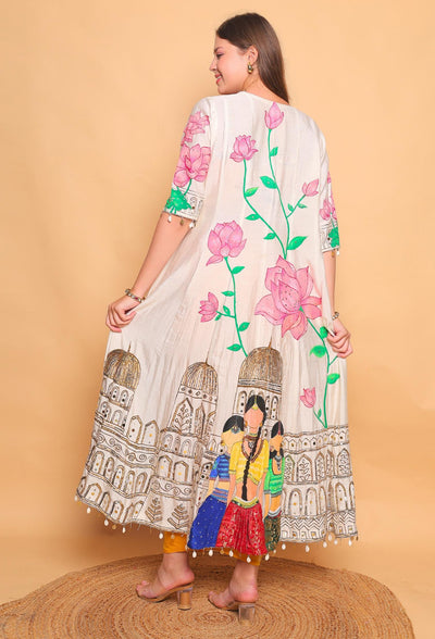 Woman wearing a white dress with colorful floral and architectural designs on a beige background
