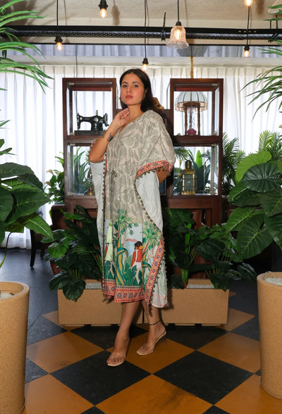 the Oasis Opulence Kaftan from Destiny by Anjali. This designer kaftan in beige and green features a stunning digital print inspired by tribal and beach women. Made from breathable cotton linen fabric, it’s perfect for all-weather wear, keeping you stylish and comfortable. Whether you're lounging at the beach or attending an occasion, this trending Western wear piece is ideal for any event. The kaftan's relaxed fit and intricate print make it a versatile choice for every occasion, blending luxury with comfo